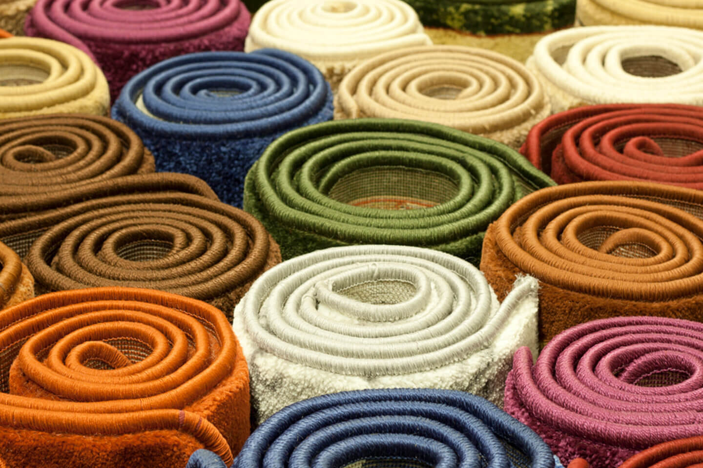 Vertical stacks of different colored rolls of carpet