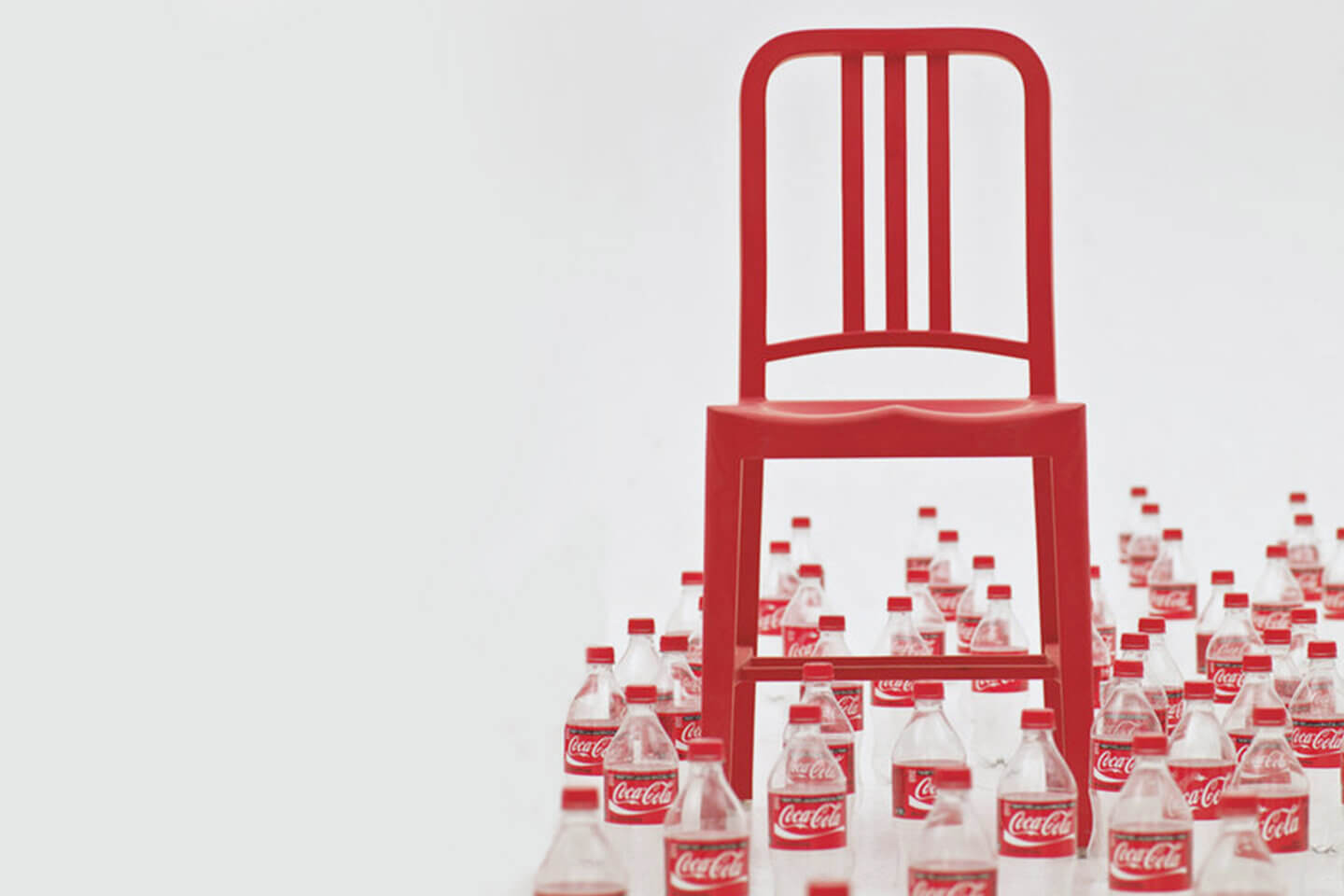 Red NAVY chair shown with a series of empty Coca-Cola bottles around it
